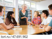 Portrait of adult female librarian and diligent schoolkids during classes in library. Стоковое фото, фотограф Яков Филимонов / Фотобанк Лори