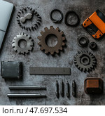 A flat lay of metal parts and precision tools arranged neatly on a textured gray surface. The composition includes gears, a ruler, cutters, bits, bushings, wrenches, and other mechanical components. Shot in an industrial style with attention to detail, shape, and texture, the photo is ideal for illustrating themes of engineering, mechanics, industrial design, and technical maintenance. Стоковое AI-изображение, AI-художник Анна Кривицкая / Фотобанк Лори
