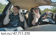 A cheerful man and woman sing and dance in the car while driving. Стоковое видео, видеограф Mikhail Davidovich / Фотобанк Лори