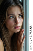 Tear-stained young woman sadly looks out the window. Стоковое AI-изображение, AI-художник Sergey Grishin / Фотобанк Лори