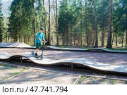 12-летний мальчик в кепке и шортах катается на самокате на памп-треке в Боровском парке в Москве весной. Стоковое фото, фотограф Яна Проничева / Фотобанк Лори