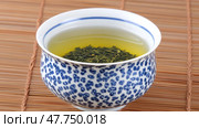 Зеленый чай в фарфоровой чашке на бамбуковом коврике для релаксации и дзен-декора. Стоковое AI-изображение, AI-художник ФотоИнтеллект / Фотобанк Лори
