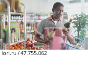 African man hold bottle and choose alcohol wine bottle in store. Стоковое видео, видеограф Яков Филимонов / Фотобанк Лори