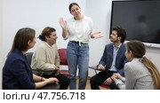 Young female teacher near interactive board, gesturing with hand in front of people sitting at desks in auditory. Стоковое видео, видеограф Яков Филимонов / Фотобанк Лори