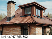 Brown metal roof with chimney, smokestack and rain gutter with downspout, ceramic tiles walls. House roof surface covered with brown metal tile sheets, plastic soffit, attic window and roof gutters created with Generative AI. Стоковое AI-изображение, AI-художник Данила Большаков / Фотобанк Лори