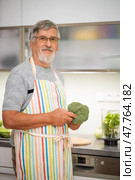 Senior man preparing broccoli, cutting broccoli at home kitchen, preparing a healthy dish full of nutrients. Стоковое фото, фотограф Viktor Cap / PantherMedia / Фотобанк Лори