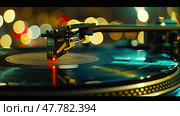A turntable needle precisely interacts with a spinning vinyl record, illuminated by a red light with soft bokeh lights in the background. Стоковое AI-изображение, AI-художник Данила Большаков / Фотобанк Лори