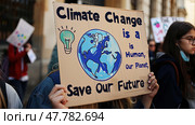People in a group are standing together, holding a sign that reads Climate change is a human issue. They are expressing their concern about the impact of climate change on people. Стоковое AI-изображение, AI-художник Данила Большаков / Фотобанк Лори