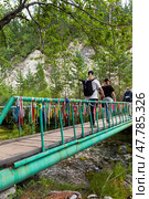 ARSHAN VILLAGE, BURYATIA, TUNKINSKIY DISTRICT, RUSSIA - July 24, 2024: Tourists walk along a suspended pedestrian bridge over the Kyngyrga River to a healing mineral spring on a summer day. Редакционное фото, фотограф Виктория Катьянова / Фотобанк Лори