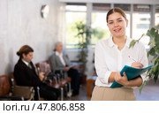 Smiling secretary girl stands at entrance to office reception and expects visitors. Стоковое фото, фотограф Яков Филимонов / Фотобанк Лори