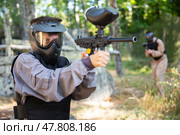 Paintball player in protective uniform aiming and shooting with guns. Стоковое фото, фотограф Яков Филимонов / Фотобанк Лори