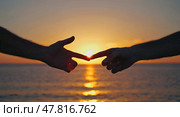 The touch of fingers against the sunset. The hands touch the other hand on the ocean shore in the rays of the setting sun. Стоковое AI-изображение, AI-художник Антон Слабоспицкий / Фотобанк Лори