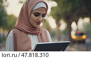 Female Muslim doctor in hijab, wearing scrubs and white coat, working with patient's records on digital tablet standing outside. Стоковое AI-видео, аниматор Ирина Старикова / Фотобанк Лори