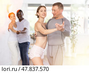 Positive young woman and adult man dancing as couple in dance studio. Стоковое фото, фотограф Яков Филимонов / Фотобанк Лори