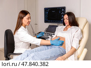 Female doctor examining pregnant woman lying on bed in clinic. Palpation of womb belly, feeling baby fetus embryo bumps. Gynecologist checkup. Стоковое фото, фотограф Ирина Михайличенко / Фотобанк Лори