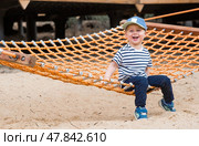 Lifestyle. A cute little boy is sitting in a hammock on a modern outdoor playground. The concept of family entertainment and leisure. Стоковое фото, фотограф Photojuli / Фотобанк Лори