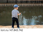 Summer lifestyle. A cute little boy is having fun playing with sand on the beach by the water. The concept of family entertainment and leisure. Стоковое фото, фотограф Photojuli / Фотобанк Лори