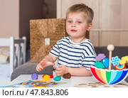 A little boy is playing with plasticine. Fine motor skills-developing games for children. The kid makes a horse. Useful games for child development. Стоковое фото, фотограф Photojuli / Фотобанк Лори