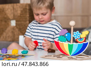 Balancing toys. A little boy is playing educational games. Children's wooden umbrella toy, colored pyramid and logic toys for children. Montessori games for child development. Стоковое фото, фотограф Photojuli / Фотобанк Лори