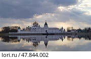 Orthodox monastery with white walls and golden domes reflected in water surface of river. Holy Trinity Ipatievsky Monastery in Kostroma. Sun rays break through dense clouds and illuminate churches. Стоковое фото, фотограф Ирина / Фотобанк Лори