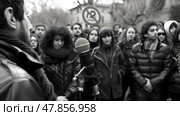 A crowd gathers around a speaker, engaged in a discussion in a public space on a chilly afternoon. Стоковое AI-изображение, AI-художник Данила Большаков / Фотобанк Лори