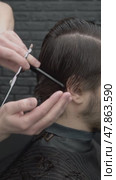 Using professional scissors, barber gathers hair between his fingers and carefully snips ends, updating brunette man s look. Vertical. Стоковое видео, видеограф Strunov David / Фотобанк Лори