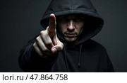 Dramatic lowkey portrait of a mysterious individual in a hooded sweatshirt with an outstretched hand emphasizing confrontation. Стоковое AI-изображение, AI-художник Андрей Бакусов / Фотобанк Лори