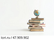 Книги с глобусом сверху, образовательная тематика, знание и обучение, место для текста. Стоковое AI-изображение, AI-художник Елена Болотина / Фотобанк Лори