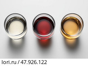 Variety of Liquors Displayed in Three Glasses on a Neutral Surface. Стоковое AI-изображение, AI-художник Юлия Гапеенко / Фотобанк Лори