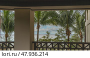 Ocean view from the resort's terrace. Spreading palm leaves against a blue sky and clouds. Turquoise sea. In the foreground are columns and latticed wooden railings. Malaysia. Borneo. Kota Kinabalu. Стоковое фото, фотограф Вера Ивановна Кубарева / Фотобанк Лори