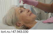 Delighted old woman lying on clinical chair in aesthetic cabinet during face RF-lifting procedure. Стоковое видео, видеограф Яков Филимонов / Фотобанк Лори