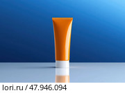 Orange white tube with suntan lotion, cosmetic face cream or hand cream, shower gel, against the blue color wall. Studio background. Blank plastic package mockup. Skincare product template. Стоковое AI-изображение, AI-художник Марина Демидюк / Фотобанк Лори