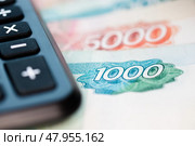 Калькулятор и деньги: банкноты 5000 и 1000 рублей (крупный план) Стоковое фото, фотограф E. O. / Фотобанк Лори