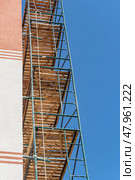 Фасад здания с установленными строительными лесами. Building under construction in scaffolding around the house for cement plastering work on the high outer wall. Стоковое фото, фотограф Татьяна Д / Фотобанк Лори