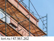 Фасад здания с установленными строительными лесами. Building under construction in scaffolding around the house for cement plastering work on the high outer wall. Стоковое фото, фотограф Татьяна Д / Фотобанк Лори