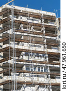 Фасад здания с установленными строительными лесами. Building under construction in scaffolding around the house for cement plastering work on the high outer wall. Стоковое фото, фотограф Татьяна Д / Фотобанк Лори