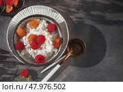 Creamed cottage cheese with raspberries. An easy healthy breakfast. A bowl filled with grainy, creamy cottage cheese is garnished with bright yellow and red raspberries. Top view. Стоковое фото, фотограф Оксана Медведева / Фотобанк Лори