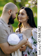 A man and a woman are lovingly holding a baby snugly in their arms. Стоковое фото, фотограф Cantemir Dumitru / Фотобанк Лори