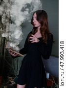 An Enchanting Sorceress is deeply engrossed in reading a Spellbook surrounded by swirling, Mystical Smoke. Стоковое фото, фотограф Anastasy Yarmolovich / Фотобанк Лори