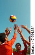 Group of people playing volleyball, one of them is about to hit the ball. Стоковое AI-изображение, AI-художник Sergey Grishin / Фотобанк Лори