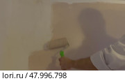 Above view of painter with cap and gloves painting a wall with paint roller, wooden vintage ladder and bucket on background. Стоковое видео, видеограф Ирина Старикова / Фотобанк Лори