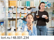 child stands and coughs in the pharmacy, and the mother chooses medications. Стоковое фото, фотограф Яков Филимонов / Фотобанк Лори