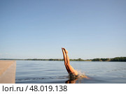 Woman in a swimsuit jumping headfirst from a pier into a lake. Capturing a powerful dive in sunlight. Стоковое фото, фотограф Скоробогатова Е. / Фотобанк Лори