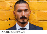 A professionally attired man stands against a bright yellow brick backdrop, exuding charisma and style. Стоковое AI-изображение, AI-художник Данила Большаков / Фотобанк Лори