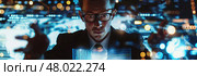 An analyst examines digital data visualizations in a modern office illuminated by glowing screens. Стоковое AI-изображение, AI-художник Данила Большаков / Фотобанк Лори