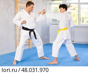 Underage boy and middle-aged man performing karate techniques in pair. Стоковое фото, фотограф Яков Филимонов / Фотобанк Лори