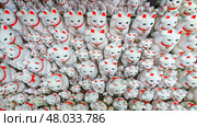Tokyo, Japan - Sep 30 2024, A close-up view of many multi-sized white beckoning cat figure of Maneki neko with red ears and noses displayed at Gotokuji Temple, without people, at daytime, Tokyo, Japan. Стоковое фото, фотограф Сергей Богомяко / Фотобанк Лори