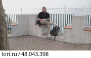 Tourist reading notes overlooking 25 de abril bridge in lisbon. Стоковое видео, видеограф Константин Шишкин / Фотобанк Лори