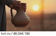 A child's small hands holding a clay water jug, symbolizing the thirst of Imam Hussain's family, under the fading light of sun. Стоковое AI-видео, аниматор Sergey Grishin / Фотобанк Лори