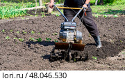 A man is using a tiller to till the soil. Стоковое фото, фотограф Скрипачев Антон / Фотобанк Лори